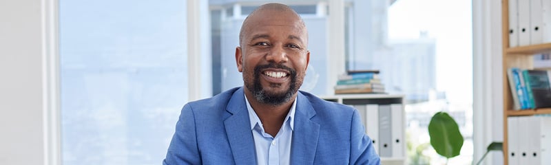 a middle-aged African-American man dressed in a suit, smiling
