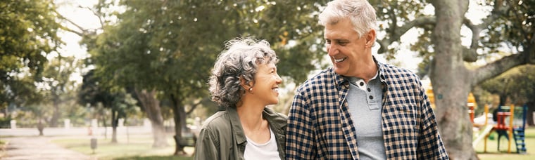 a middle-aged couple holding hands walking through a park