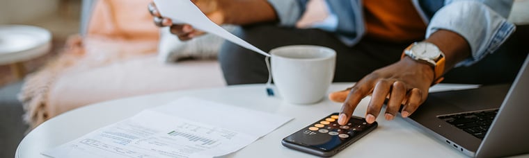 close-up picture of someone looking at a paper with a calculator on the table