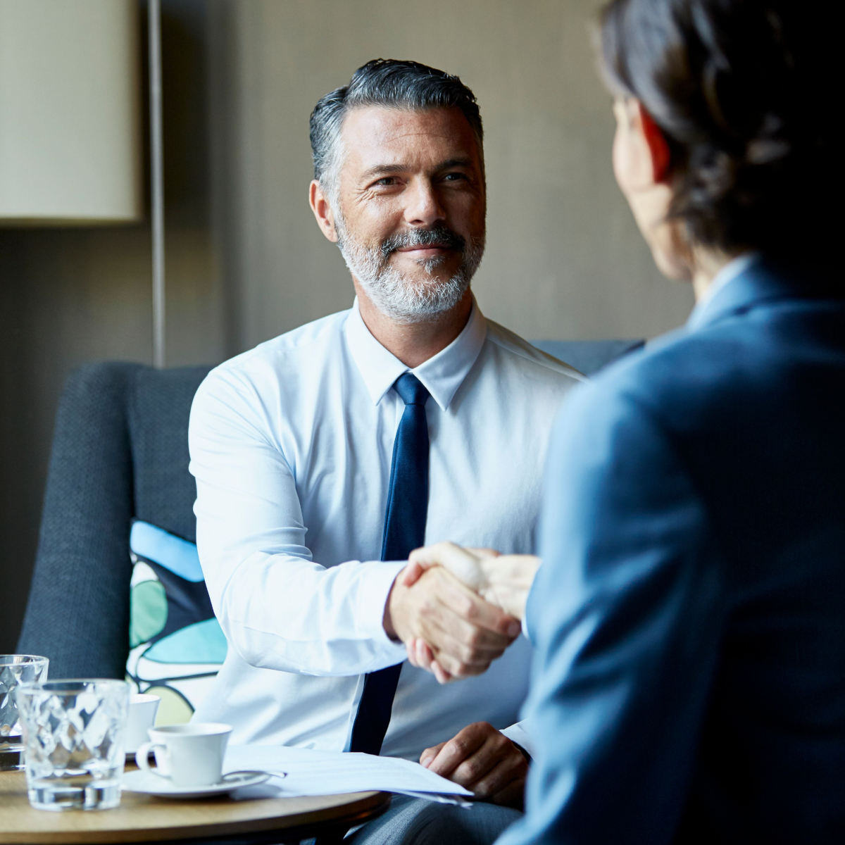 A male Allworth financial Advisor smiling and shaking hands with a client during a financial planning meeting 