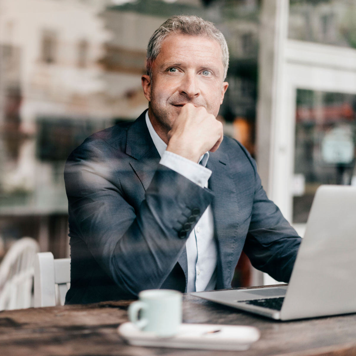 Man sitting at a coffee shop while looking out over his laptop