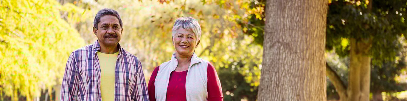 Older couple smiling and walking through a sunny, autumn park scene Older couple smiling and walking through a sunny, autumn park scene