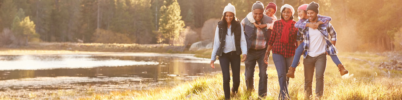 A multigenerational family happily taking a walk along side a river.