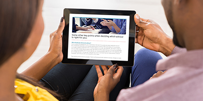 couple on their couch looking at their tablet displaying the guide on how to select a financial advisor